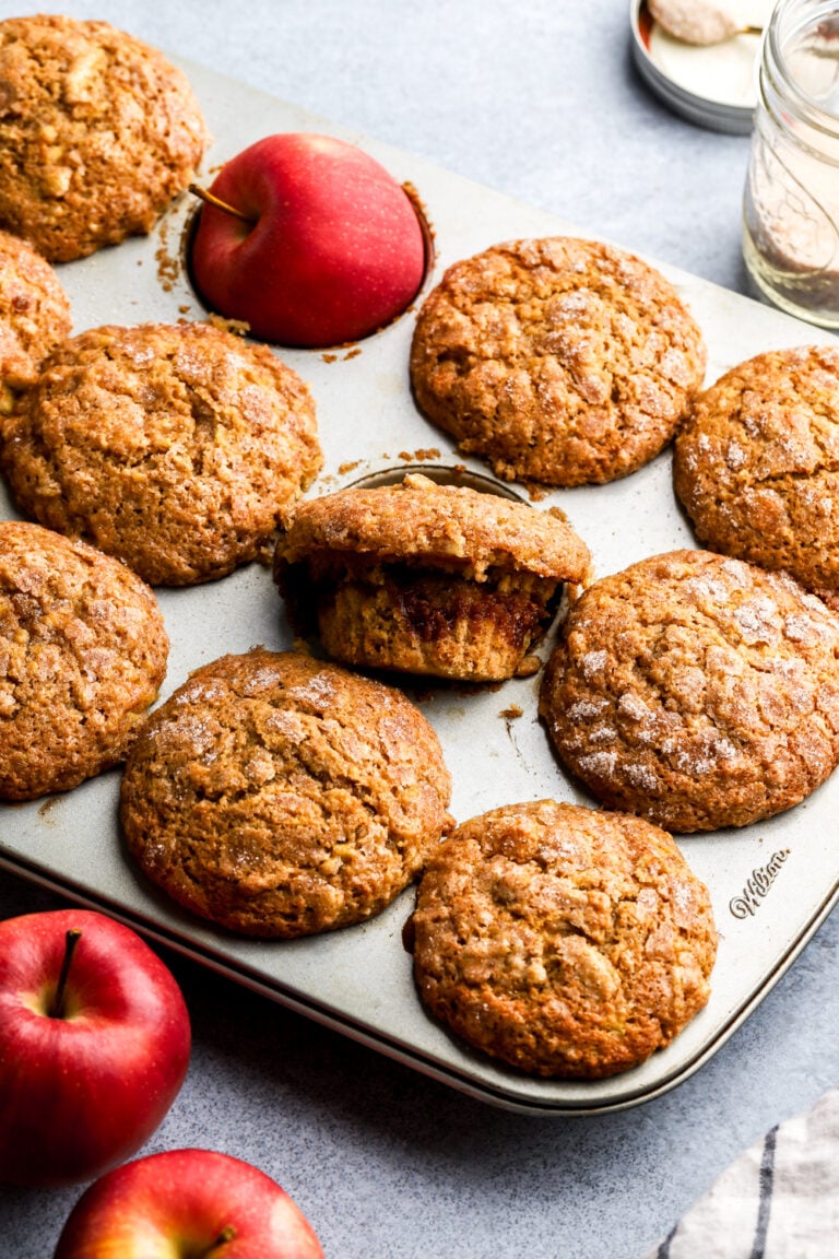 Apple muffins in a baking pan with red apples