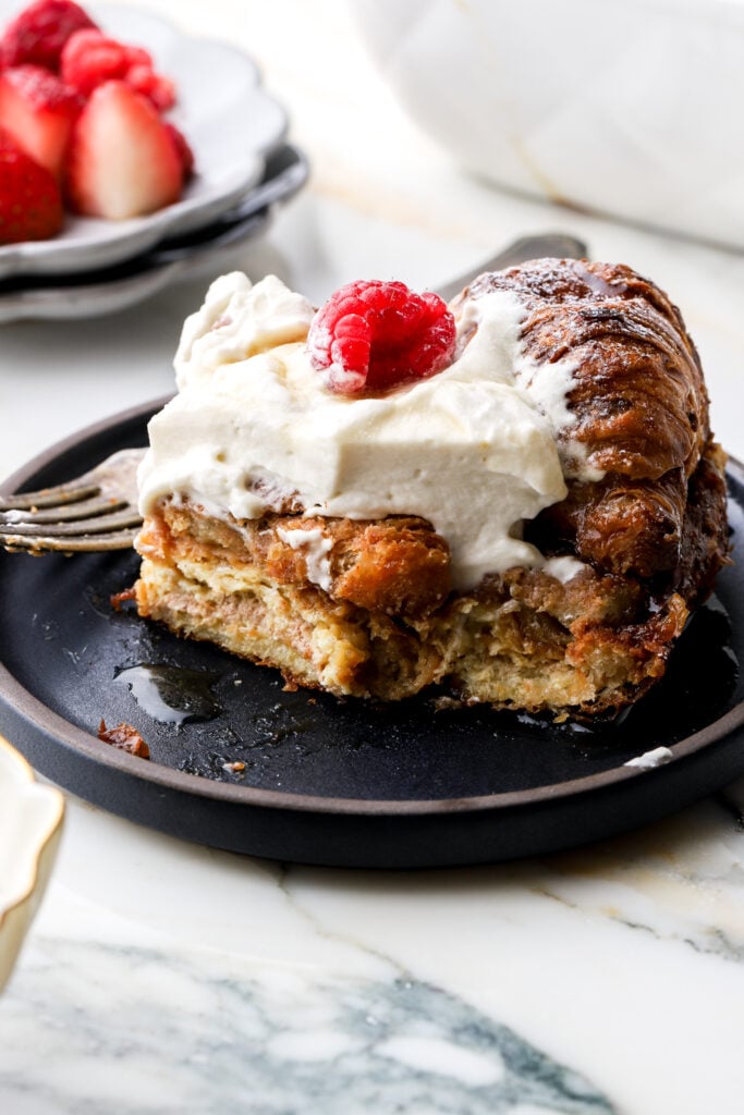 slice of croissant french toast on a plate topped with whipped cream