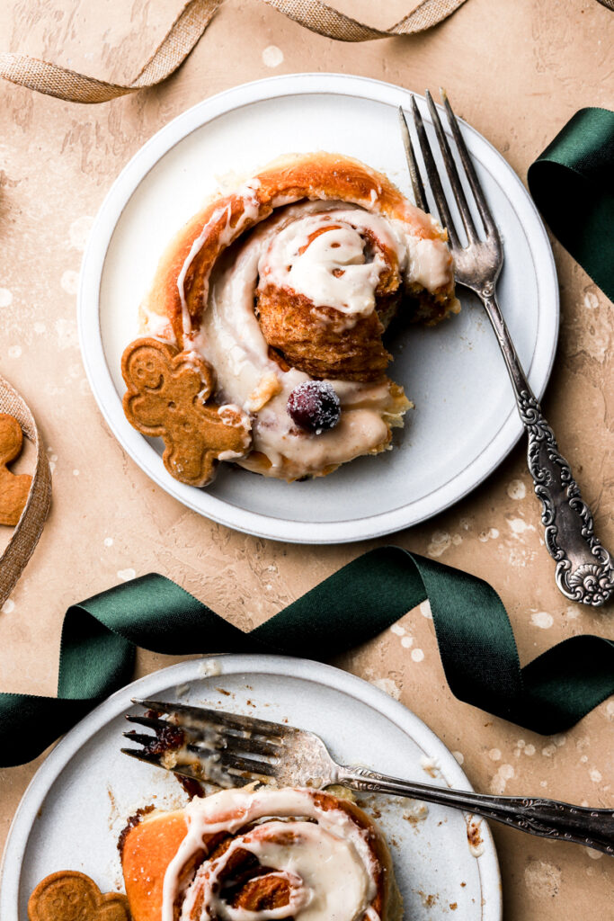 two cinnamon rolls on plates with icing and fork