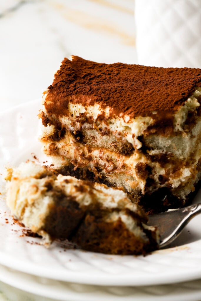 tiramisu on a plate with a bite taken out