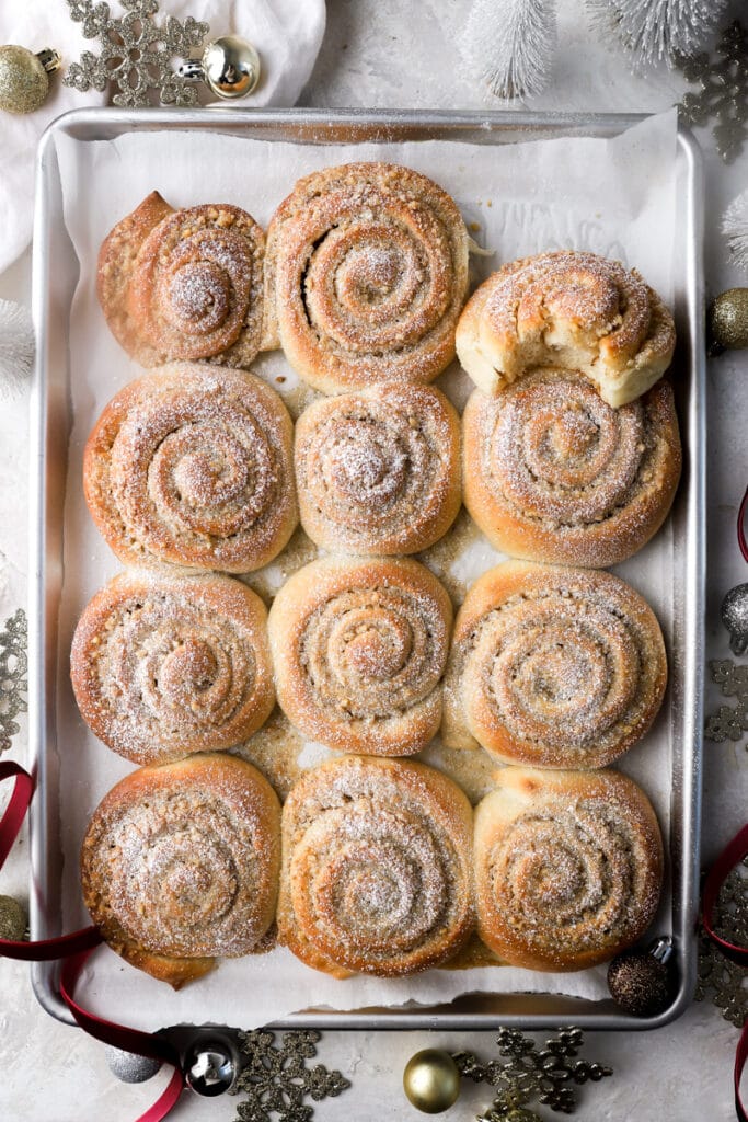 12 walnut rolls on a tray dusted with powdered sugar