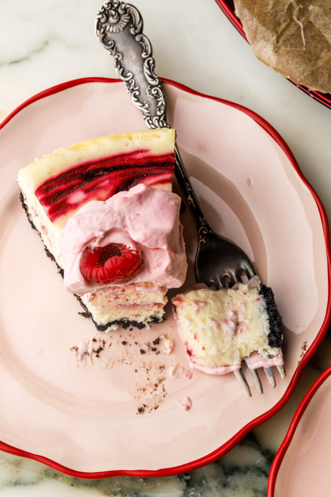 slice of white chocolate raspberry cheesecake with a bite taken out